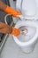 Hands in Orange gloves cleaning WC, Toilet, lavatory using brush