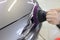 Hands with orbital polisher in car workshop polishing headlight of car