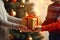 Hands of parent giving Christmas gift on Christmas tree background