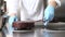 Hands pastry chef prepares a cake, cover pouring chocolate icing, working on stainless steel industrial kitchen work top