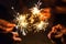 Hands of people holding sparkler, Bright festive Christmas sparkler