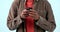 Hands, phone and man typing in studio isolated on blue background. Smartphone, closeup and person scroll on internet