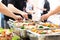 Hands picking up food from buffet catering table at the party