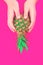 Hands with pineapple on summer neon pink background