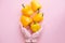 Hands in pink glove holding yellow peppers on pink background flat lay. Order groceries and get them delivered safe during