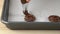 Hands piping chocolate cookies on baking tray