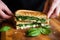 hands placing fresh basil leaves on a grilled cheese sandwich
