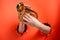 Hands playing pocket trumpet torn holes in red paper background