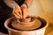 Hands of potte makes pottery dishes on potter`s wheel. Sculptor in workshop makes clay product
