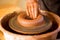 Hands of potter makes pottery dishes on potter wheel. Sculptor in workshop makes clay product