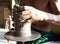 Hands of a potter manufactures clay pot