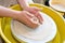 The hands of a potter sculpting a piece of clay on a rotating potter\'s wheel