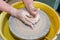 The hands of a potter sculpting a piece of clay on a rotating potter\'s wheel