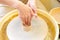 The hands of a potter sculpting a piece of clay on a rotating potter\'s wheel