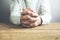 Hands of praying young man on a wooden desk background