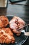 Hands prepare for eating fresh sweet bake croissant by use a fork and knife for cutting on a black plate for breakfast over in gar