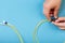 Hands prepare to tune a variable optic attenuator with a screwdriver. Blue background