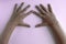 Hands of preschool girl with dirty long nails on a pink background