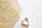 Hands pressing heart shaped cookie cutter into dough