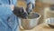 Hands of professional cook in black rubber gloves mixing salad with seasoning in the aluminum bowl using the spoon in