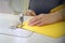 Hands of a professional seamstress sewing details of bright yellow fabric.