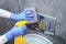 Hands in protective gloves cleaning toilet flush button