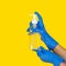 Hands in protective surgical gloves hold a bottle of gel sanitizer with a pump.