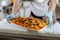 Hands putting on a dish with chicken snacks and carrot on distribution desk