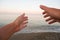 Hands reaches for the sunset against the background of the sea