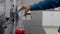 Hands of a research scientist pouring a colorless chemical from a bottle to a red colored chemical in a conical flask