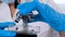 Hands of a researcher laboratory assistant in protective gloves holding a microscope in the laboratory, close up.