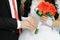 Hands and rings with wedding bouquet of orange gerberas