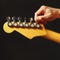 Hands of rock guitarist tunes the electric guitar on black background