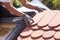 Hands of roofer laying tile on the roof. Installing natural red tile