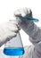 Hands in rubber gloves pour a blue chemical liquid in a flask, on a white background