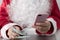 Hands of Santa Claus holding money, dollars and smartphone