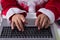 Hands of Santa Claus typing at laptop keyboard