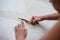 Hands with scissors with blue handles, cutting paper pattern with light beige fabric. Close-up picture of cutting process. Sewing