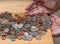 Hands scooping up loose USA change with mixed coins on wooden table