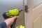 Hands screwing hinge on wooden door with screwdriver
