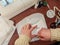 Hands of a seamstress outline in yellow chalk on a white fabric a paper pattern of a protective medical face mask, top view. Stage