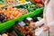 The hands of a senior woman choose onions at the supermarket. A counter full of various types of vegetables for a healthy diet