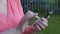 Hands of senior woman touching screen mobile phone in summer garden