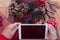 Hands of a senior woman using technology with a small tablet. Wooden table decorated with Christmas accessories