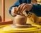 Hands shaping clay on potter wheel crafting clay pot in pottery studio, world art day image