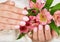 Hands with short manicured nails colored with pink nail polish