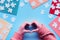 Hands show heart sign. Jigsaw puzzle elements and multicolor felt sheets on blue background.