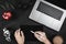 Hands showing digital tablet blank screen on work desk. Modern workspace with camera, laptop keyboard, coffee cup and apple