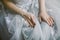 Hands of sitting bride in a grey lace dress. Bridal fashion.