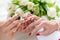 Hands of a skilled manicurist applying red nail polish on nails